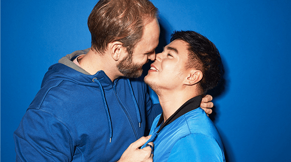 blauer Hintergrund, ein Mann küsst einen anderen Mann